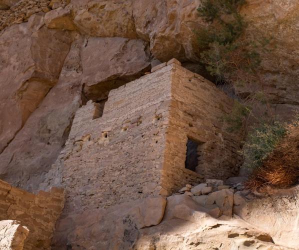 A stone structure constructed into a cliff ledge.