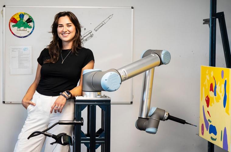 CEO Chloe Ryan leans on a robot as it creates a new painting.