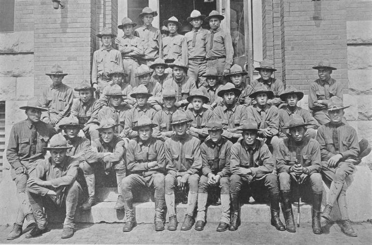 Black and white image of a large group of US Army soldiers outside a brick building.