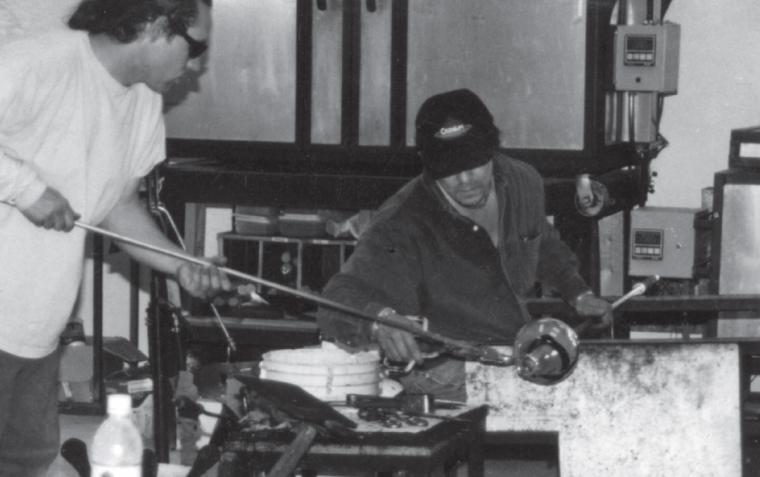 Robert "Spooner" Marcus and Tony Jojola work on a glass piece in a studio.