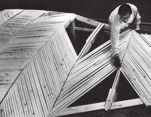 An aerial view of Truman Lowe working on a wood sculpture
