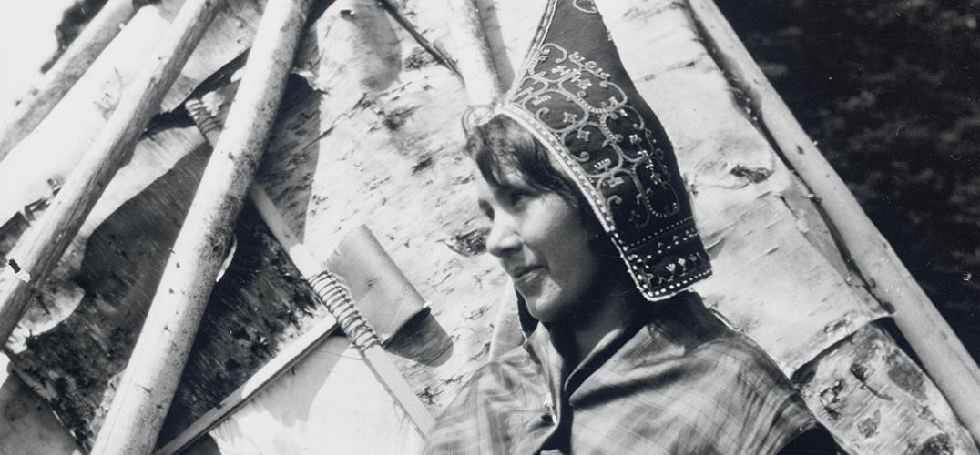 A black and white image of a woman wearing a peaked cap embroidered with swirling patterns