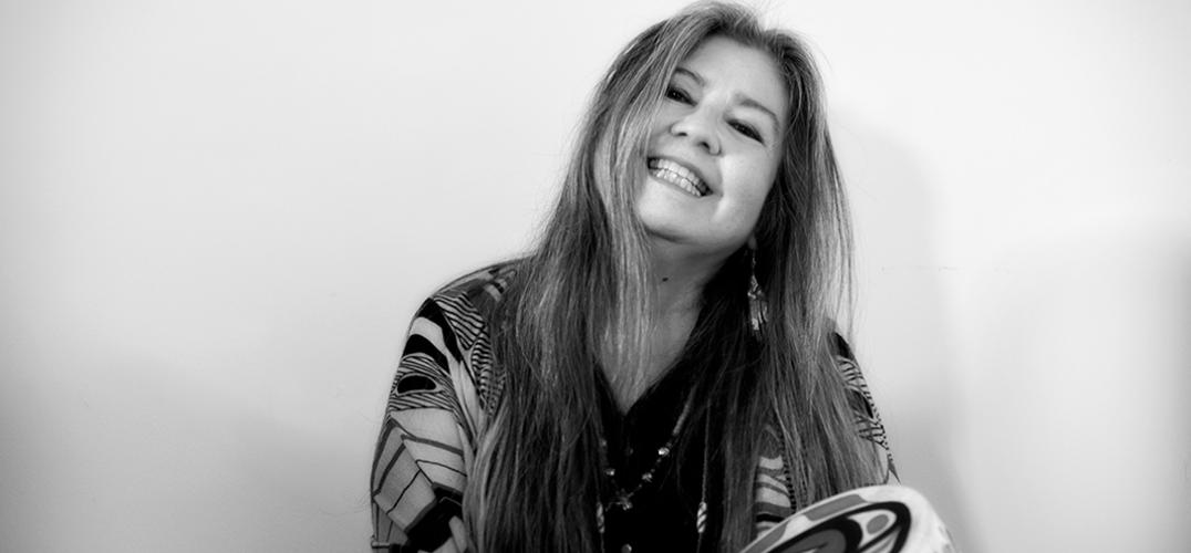 A black and white portrait of the poet Donna Beaver holding a hand drum