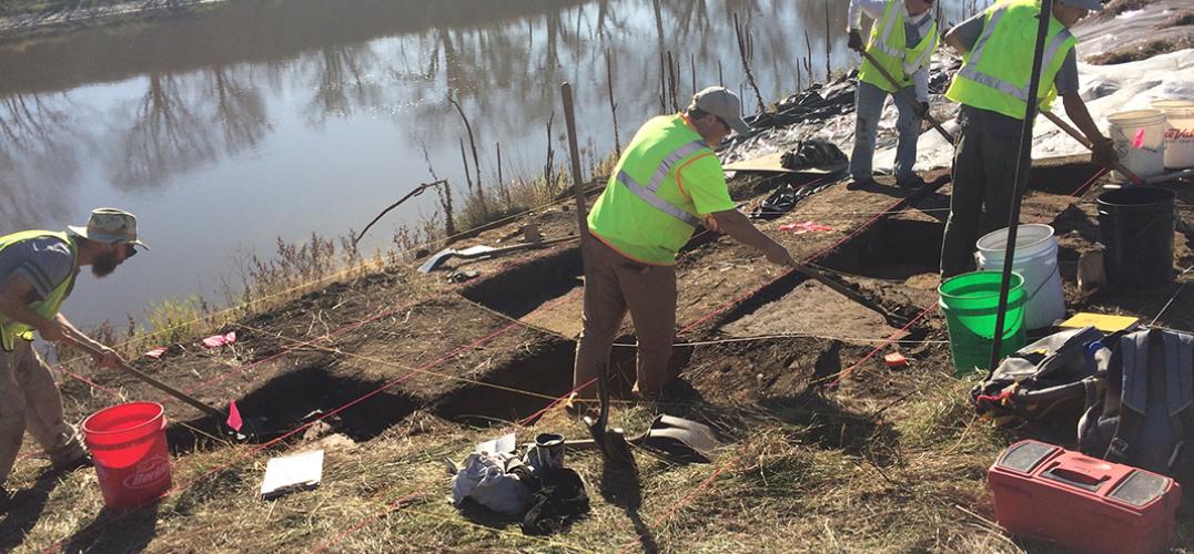 Archaeology crew members work along a riverbed in Iowa