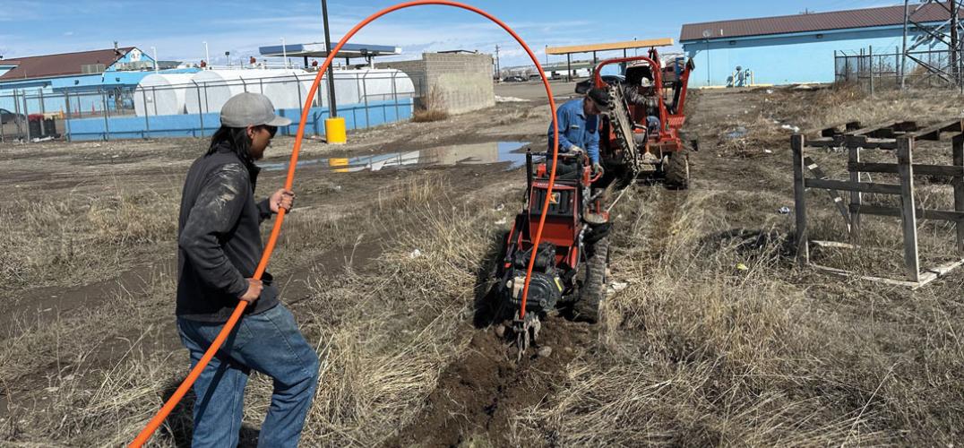 Two men use machinery to prepare the ground for fiber optic cable installation