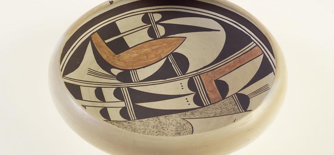 A shallow, cream ceramic bowl with black and brown designs