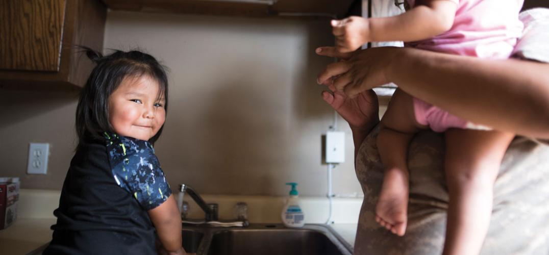 A child smiles while water runs through a tap