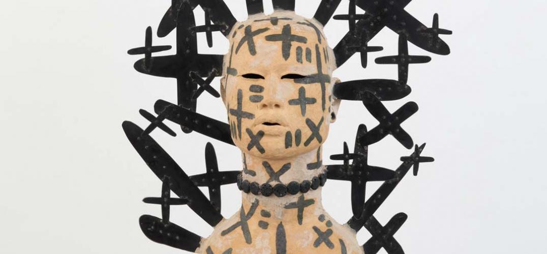 Sculpture of human form surrounded by black plus signs and x's.