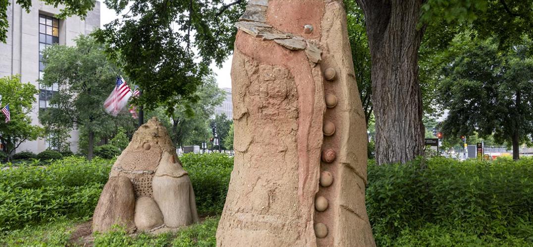 Clay scupltures Mountain Bird and Moon Woman and displayed in front of the NMAI amongst lush greenery.