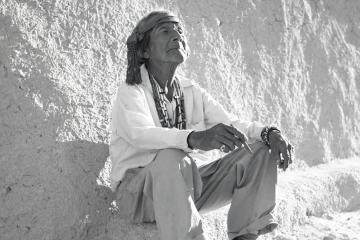 Elderly man sitting against a wall