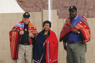 Lula Bia stands in front of her son's flag with his former comrades, Terry Ash and Arthur Corley.