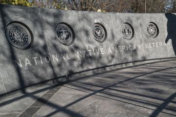 A granite wall featuring the emblems of the branches of the military: the Army, Marine Corps, Navy, Air Force and Coast Guard. 