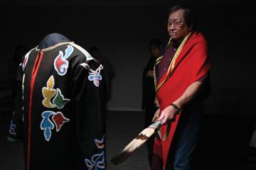 Eddy Red Eagle Jr. greets a beaded coat of his Osage ancestors