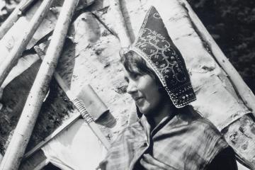 A black and white image of a woman wearing a peaked cap embroidered with swirling patterns