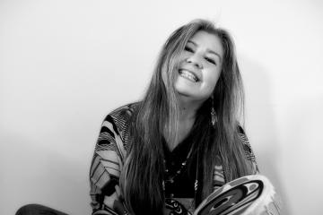 A black and white portrait of the poet Donna Beaver holding a hand drum