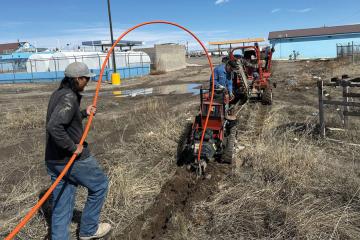 Two men use machinery to prepare the ground for fiber optic cable installation