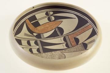A shallow, cream ceramic bowl with black and brown designs