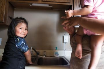 A child smiles while water runs through a tap