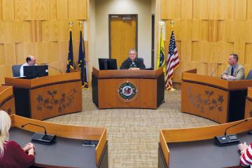 A courtroom with people, including a judge, sitting at tables arranged in a circle