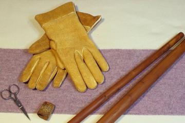 Handmade gloves and tools used to make them, laid out on a blanket