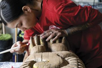 Artist Nakesha Edwards working on a wooden totem pole.