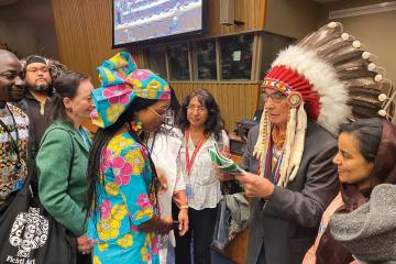 Chief Wilton Littlechild, wearing a headdress, accepts a peacemaking docume
