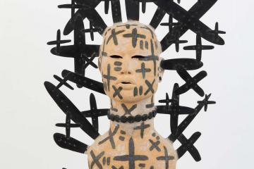 Sculpture of human form surrounded by black plus signs and x's.
