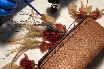 A gloved hand gently removes crystals from delicate artifacts.