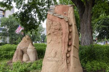 Clay scupltures Mountain Bird and Moon Woman and displayed in front of the NMAI amongst lush greenery.